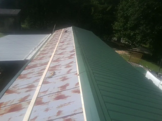 Old rusted panels beside newly installed green metal roofing — Wind Damage Roof Repair by Roofing Brothers in Grand Ronde