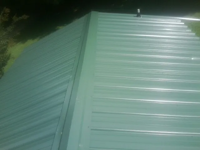 New green metal panels meeting at the ridge of a roof — Flat Roof Repair work by our crew in Grand Ronde
