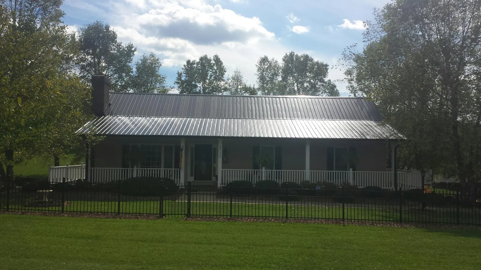 Gray metal roof on a brick ranch with a full width front porch — Gutter Guard Installation work by our crew in Grand Ronde