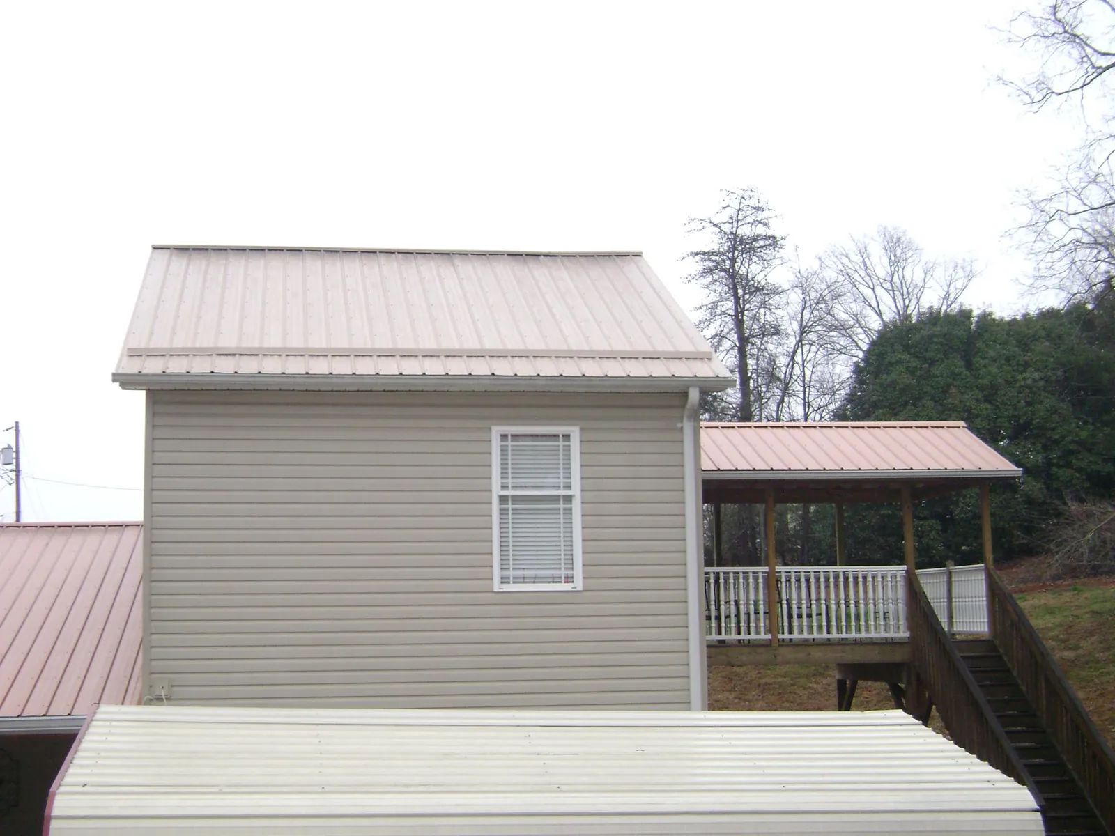 Tan metal roofs on a two story addition and attached porch, from a Roof Replacement job in Grand Ronde