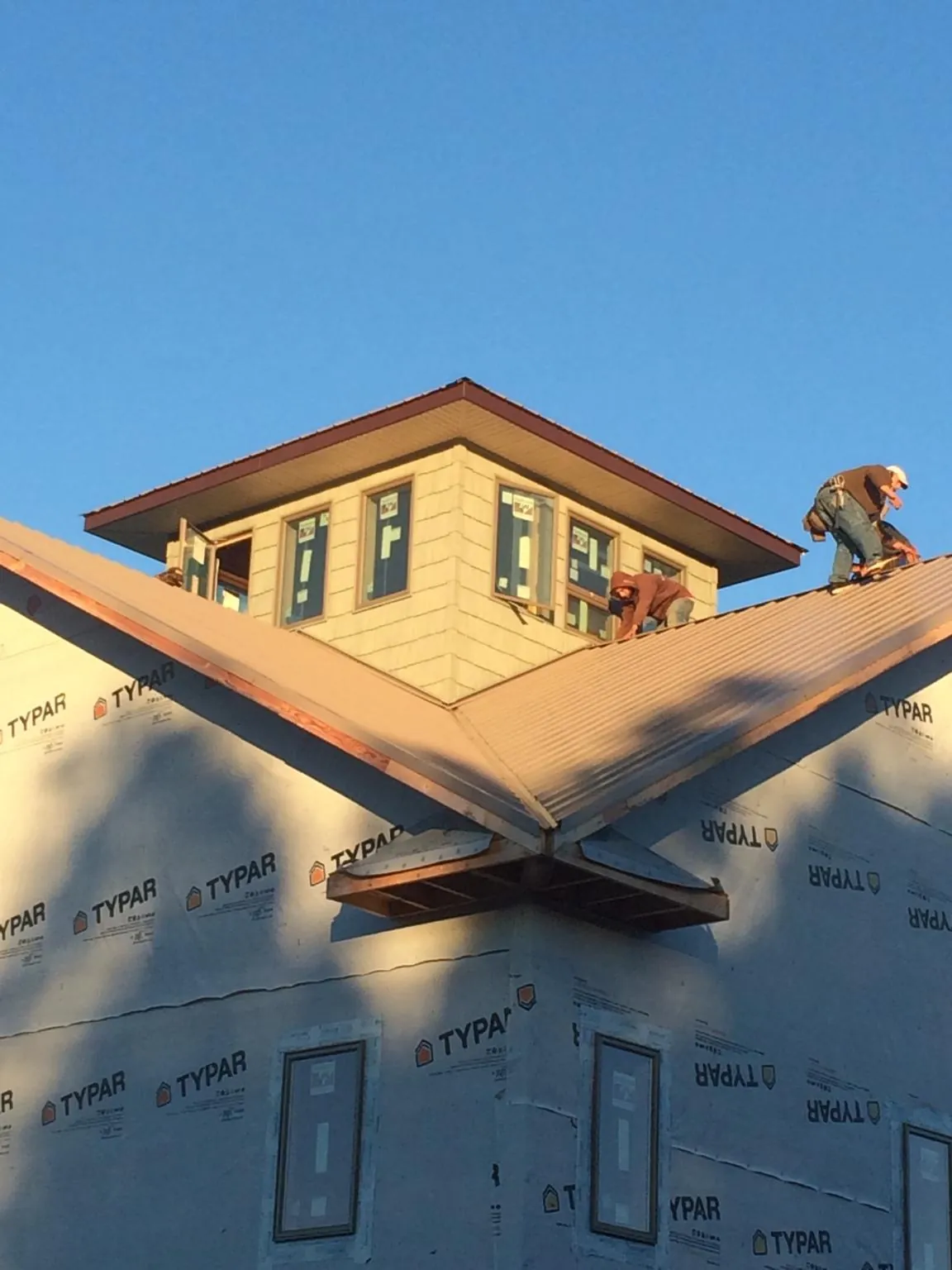 Roofers working around a rooftop cupola on a new metal roof at sunset — Roof Waterproofing in Grand Ronde by Roofing Brothers